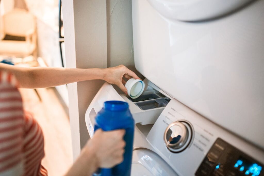 A Person Pouring Detergent in a Washing Machine